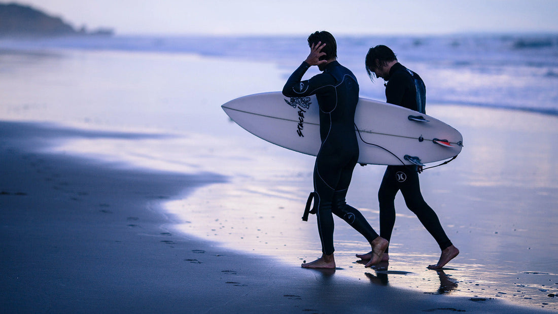 two surfers walking up the beach