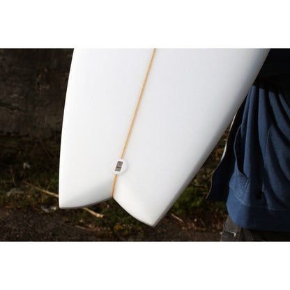 White surfboard with fish tail and leash plug on a image background and white border.